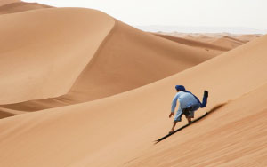 Sandboarding down Saharan dunes in Morocco